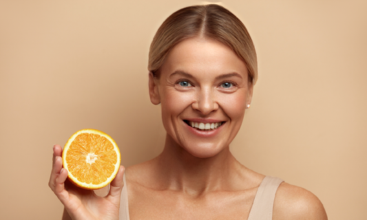 Mature woman smiling while holding half of an orange